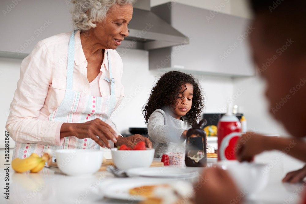 Grandmother In Kitchen With Grandchildren Making Pancakes Together Grandmother In Kitchen With Grandchildren Making Pancakes Together