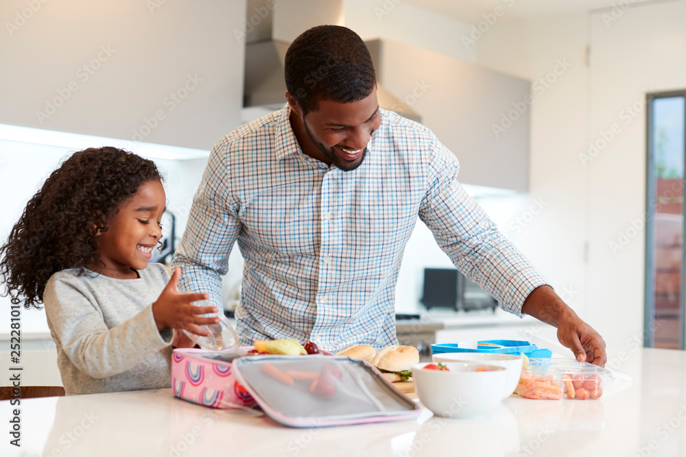Daughter In Kitchen At Home Helping Father To Make Healthy Packed Lunch Daughter In Kitchen At Home Helping Father To Make Healthy Packed Lunch