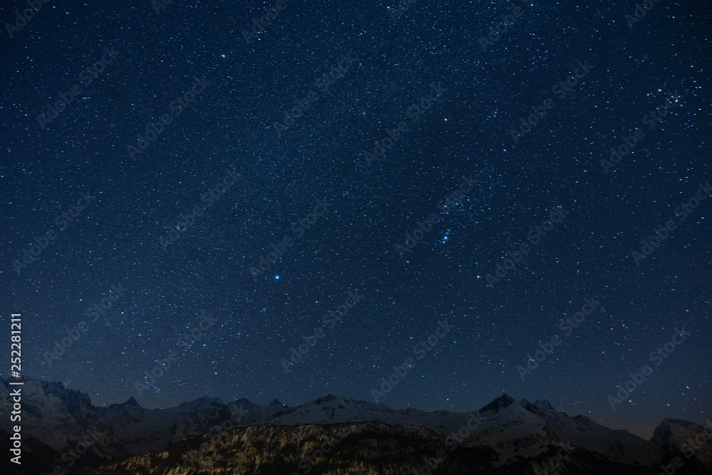 Herrliches Sternenmeer mit tintenblauem Himmel in klarer Nacht über schneebedeckten Bergen in Hohfluh auf dem Hasliberg im Berner Oberland, Schweiz. Viel Platz für Text. Konzeptuell.