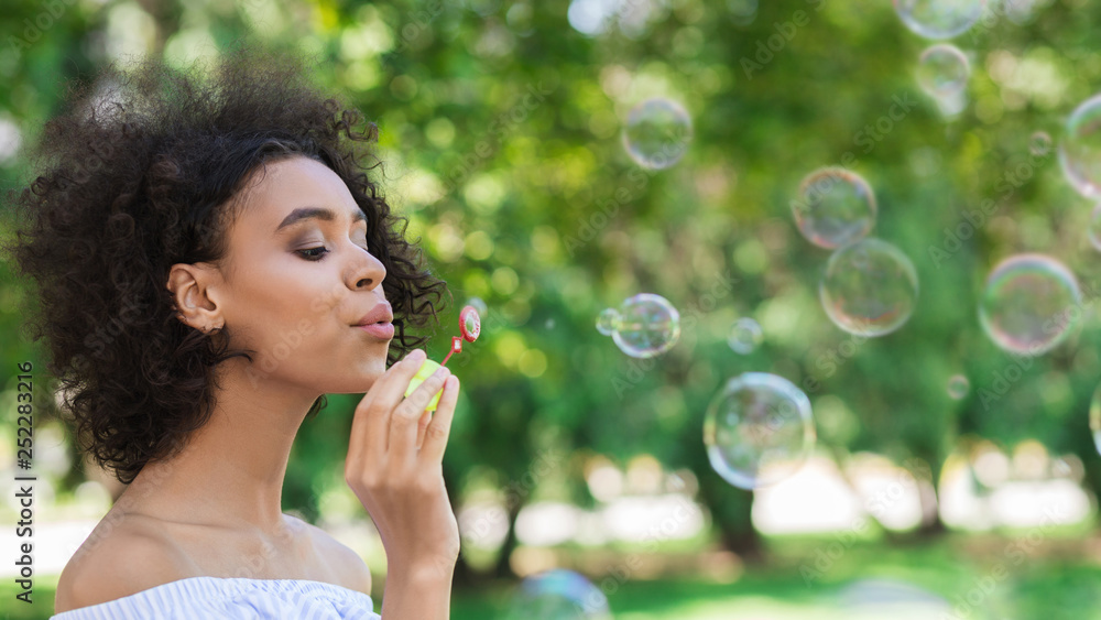 Portrait of young beautiful woman making soap bubbles
