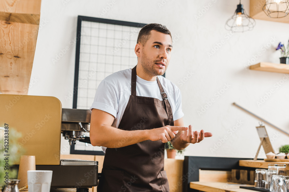 bearded barista in apron using shaker while working near coffee machine in  coffee shop Stock Photo by LightFieldStudios