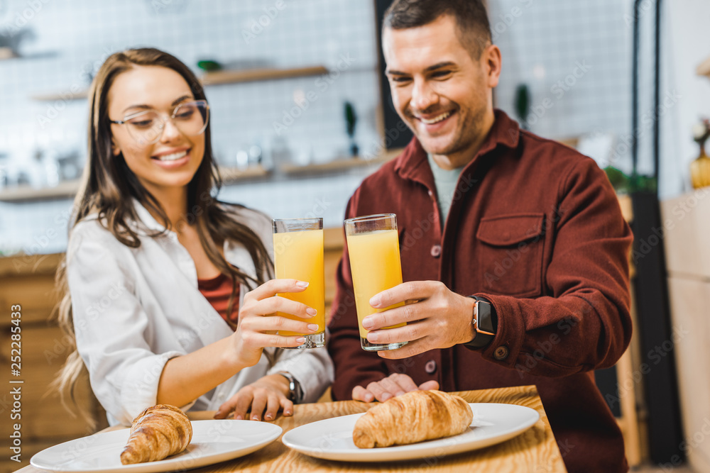 selective focus of glasses with juice in woman and man hands sitting at table with croissants in coffee house selective focus of glasses with juice in woman and man hands sitting at table with croissants in coffee house