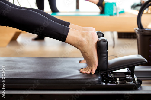 Woman training on Pilates reformer in a pilates class, detail on the legs