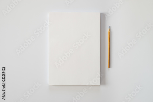 A stack of blank sheets of paper and a pencil on a white background
