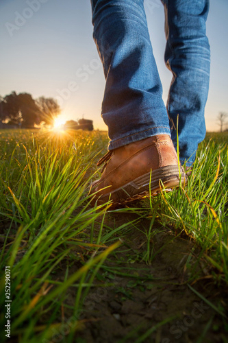  a walks farmer's work shoes in his field towards his tractor 