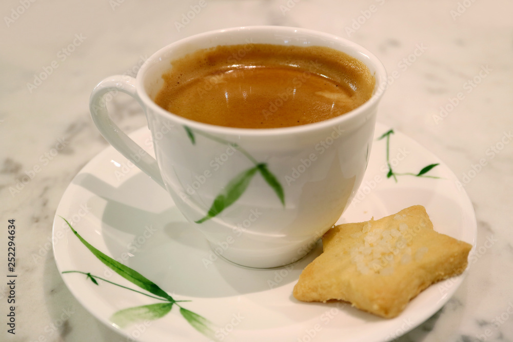 Cup of hot coffee with star shaped butter cookie served on white table Cup of hot coffee with star shaped butter cookie served on white table