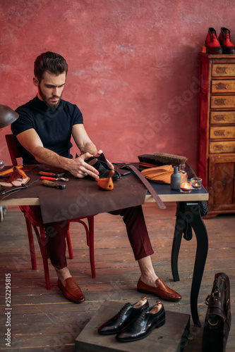 young attractive cobbler measuring the leather for shoe. measurement, full length photo photo