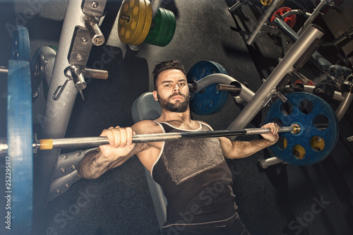 Young muscular man doing bench press at the gym