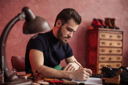 young attractive man modelling design of shoes at workshop, close up side view photo