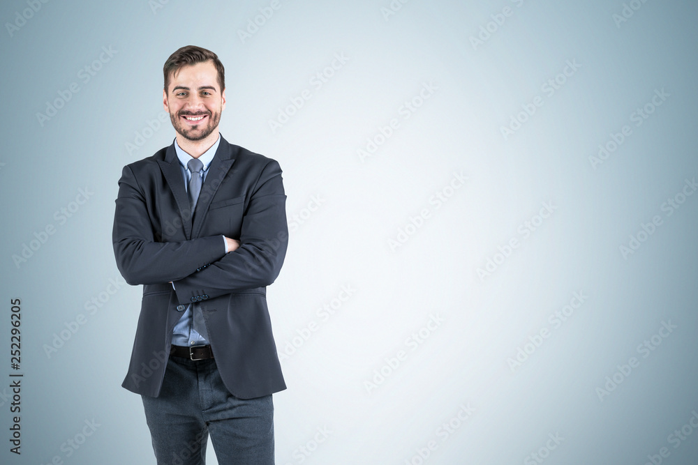 Smiling businessman with crossed arms, gray wall Smiling businessman with crossed arms, gray wall