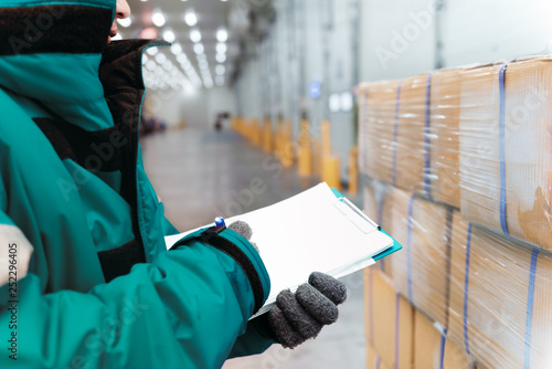 Schilderij op canvas Hand of worker with clipboard checking goods in freezing room or warehouse