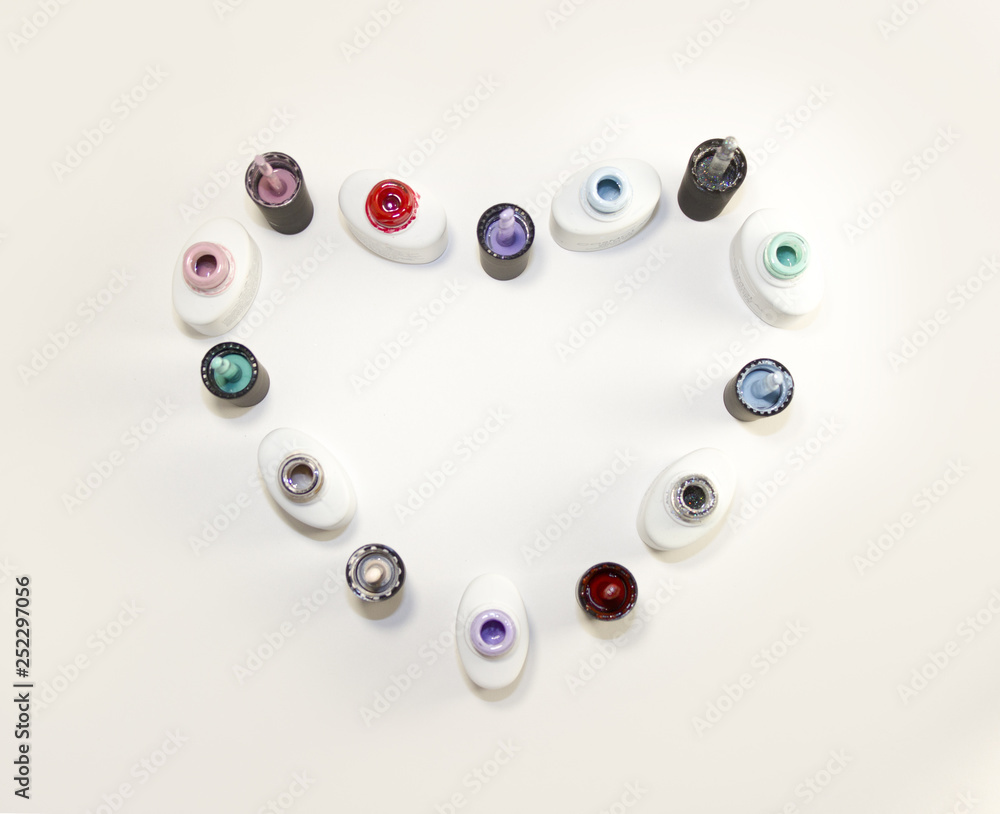 Bottles of nail Polish in the form of a heart on a white background. The view from the top. Bottles of nail Polish in the form of a heart on a white background. The view from the top.
