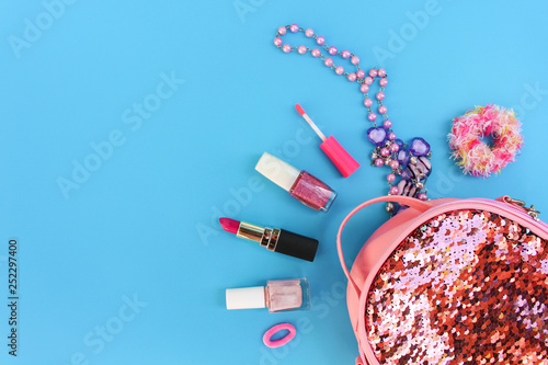 Female backpack with cosmetics and women's accessories on blue background. Top view, flat lay. photo