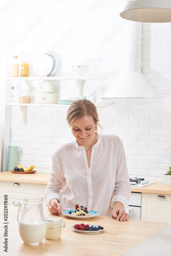 happy young woman preparing tasty snacks at the kitchen table in the morning light happy young woman preparing tasty snacks at the kitchen table in the morning light