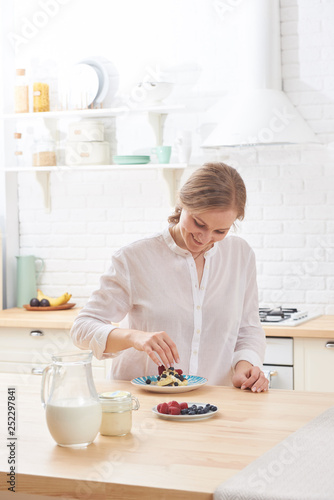 happy young woman preparing tasty snacks at the kitchen table in the morning light