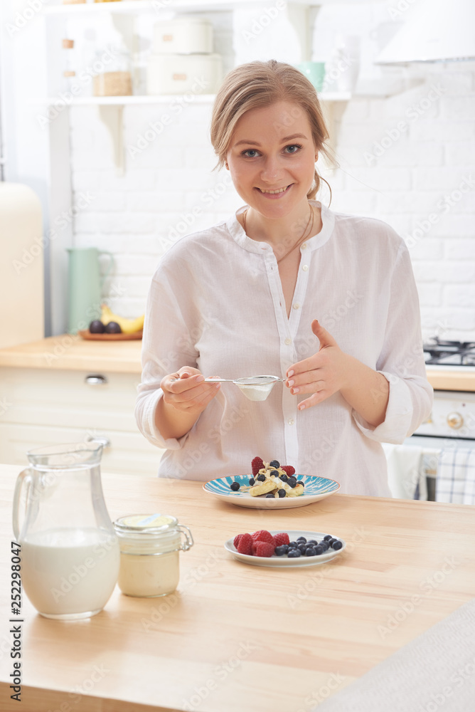 happy young woman preparing tasty snacks at the kitchen table in the morning light