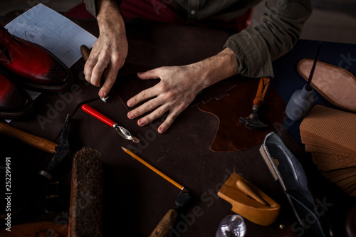 man's hands cutting details for shoes, creating of trendy footwear. close up cropped photo