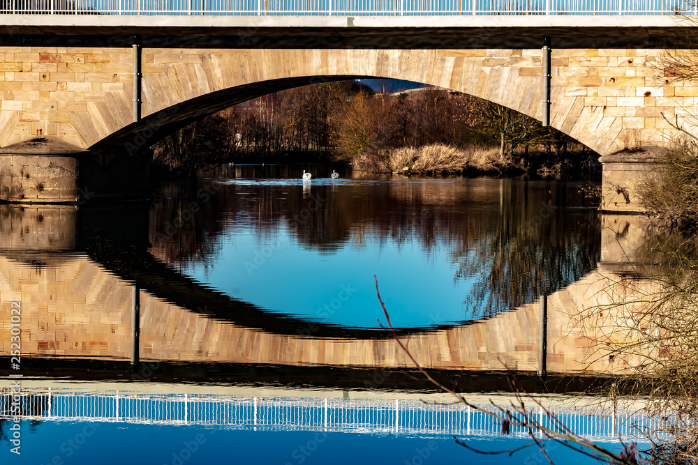 Winter landscape, Marburg, Germany - A beautiful reflection of the old land bridge of the B3, over the Lahn, in Argenstein near Weimar. On a day in February with cloudless blue sky.