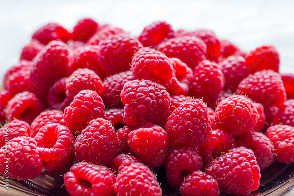 Red raspberries on a plate close-up, berries for consumption_