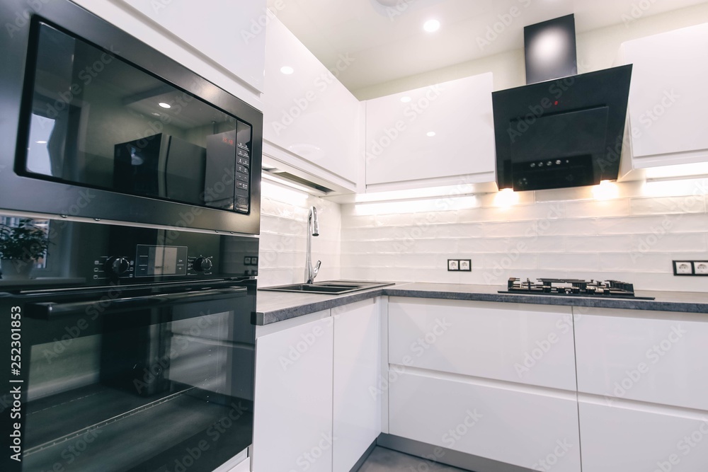 Fototapeta premium modern white kitchen interior with &nbsp; LED backlight. Household appliances oven, gas stove, hood.