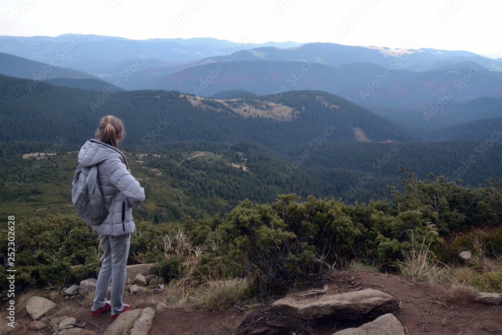 girl at the top of the mountain looks at the horizon. majestic nature, forests and outdoor activities girl at the top of the mountain looks at the horizon. majestic nature, forests and outdoor activities