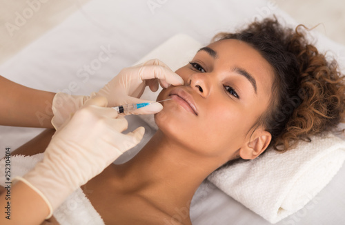 Lip augmentation. Young woman receiving acid injection