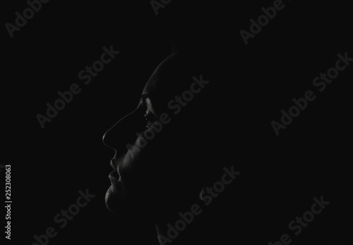 The outlines of a woman s face in profile immersed in dark black shadows