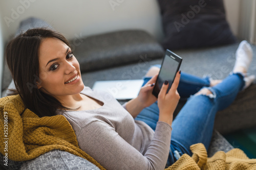 woman sitting sofa and usit tablet in her home