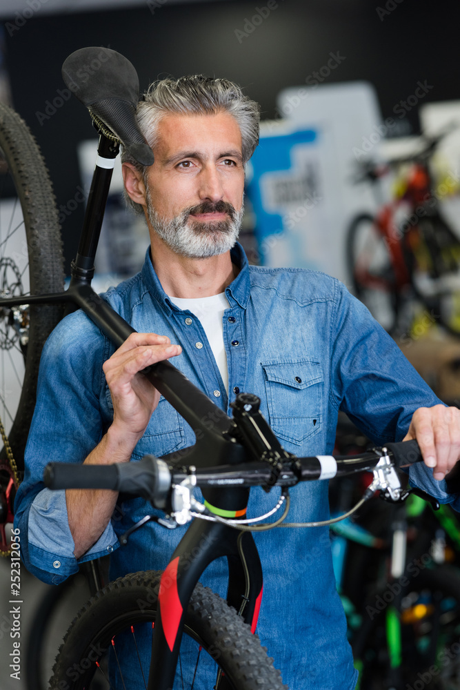 male smiling master holding a bike in a special workshop