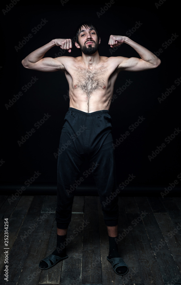 A young man in his pants on a black background
