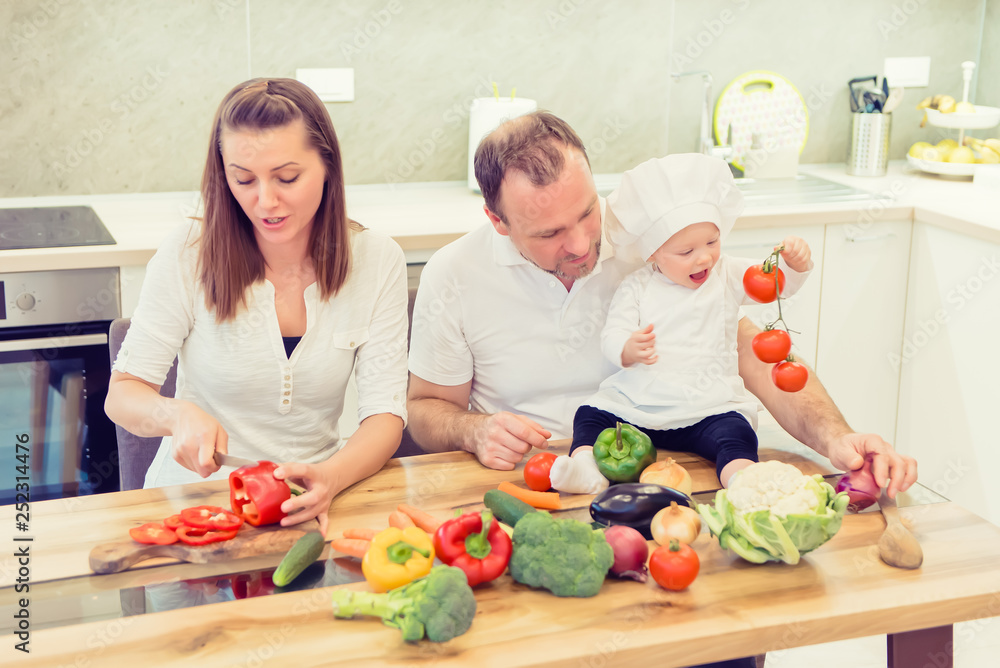 Happy parents sitting in the kitchen and prepares for cooking with their baby girl chef. Happy parents sitting in the kitchen and prepares for cooking with their baby girl chef.