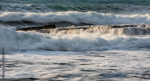Rocky seashore with wavy ocean and waves crashing on the rocks