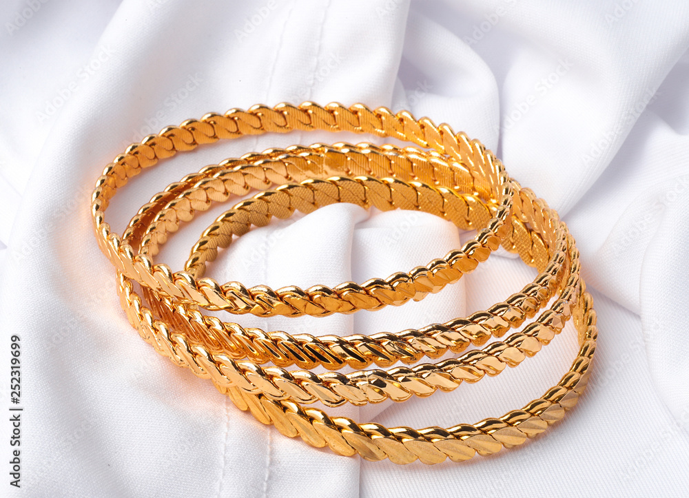 four golden bracelets on white background 