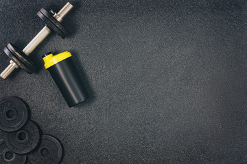 Fitness or bodybuilding concept background. Product photograph of old iron dumbbells on black grey, conrete floor in the gym. Photograph taken from above, top view with lots of copy space