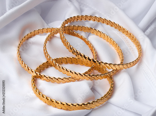 four golden bracelets on white background 