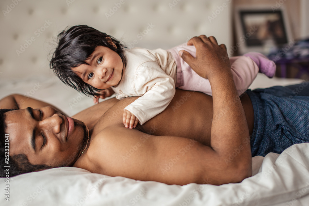 smiling little baby having a rest on her father's stomack, close up side view photo. preparation for sleeping smiling little baby having a rest on her father's stomack, close up side view photo. preparation for sleeping