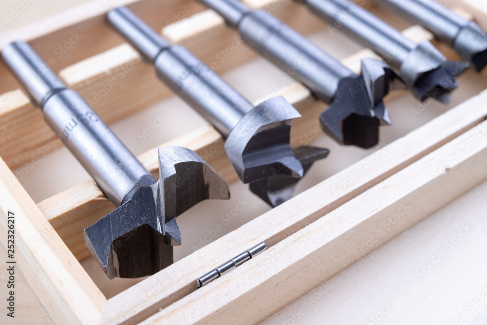 Carpentry drill, used to mount furniture hinges. A cutter used to mount furniture from chipboard. Dark background.