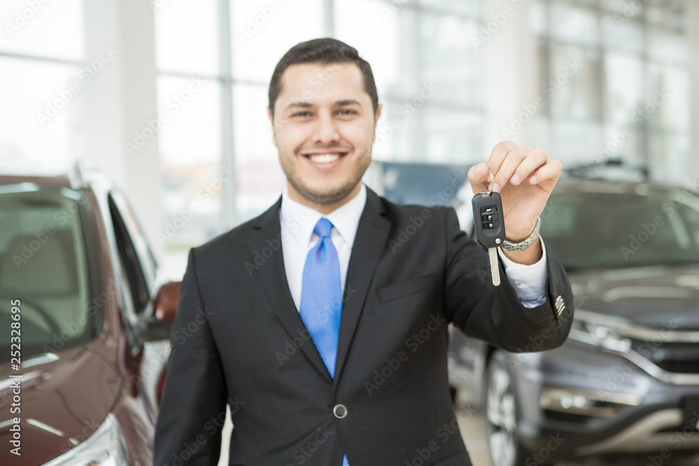Cheerful car dealer posing at his auto showroom