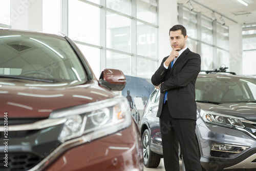 Handsome young businessman choosing a new car at the dealership salon © Zoriana