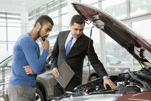 Young African man buying a car from a professional salesman