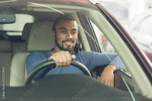 Cheerful young man sitting in his new automobile