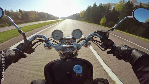 Fast motorcycle riding on highway towards sun, wide point of view of rider. Classic cruiser/chopper forever! 