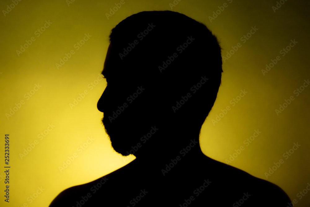 Cleanly defined silhouette of a male person turned to the left against a  yellow background with