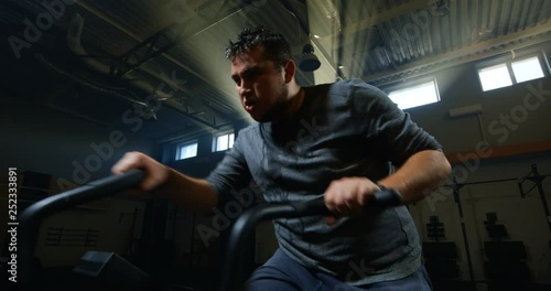 Overweight young man exercising with a machine