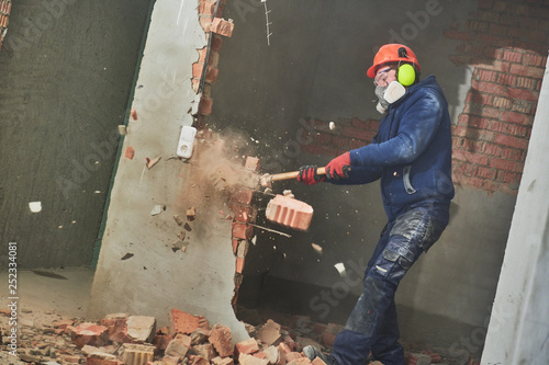 demolition work and rearrangement. worker with sledgehammer destroying wall