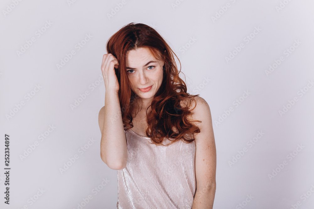 Close up portrait of young ginger pretty emotional caucasian girl with freckles posing in studio on grey background. Beauty, casual, fashion concept Close up portrait of young ginger pretty emotional caucasian girl with freckles posing in studio on grey background. Beauty, casual, fashion concept