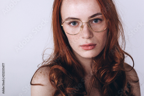 Young serious tender depressed woman on grey background