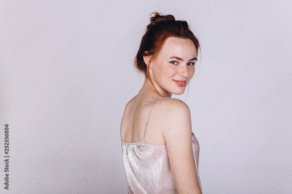 Close up isolated portrait of young cheerful ginger girl with freckled body on grey background. Beauty, emotions concept Close up isolated portrait of young cheerful ginger girl with freckled body on grey background. Beauty, emotions concept