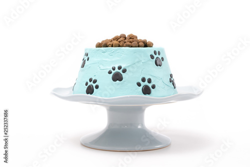 Dog food birthday cake on a cake stand isolated on white background