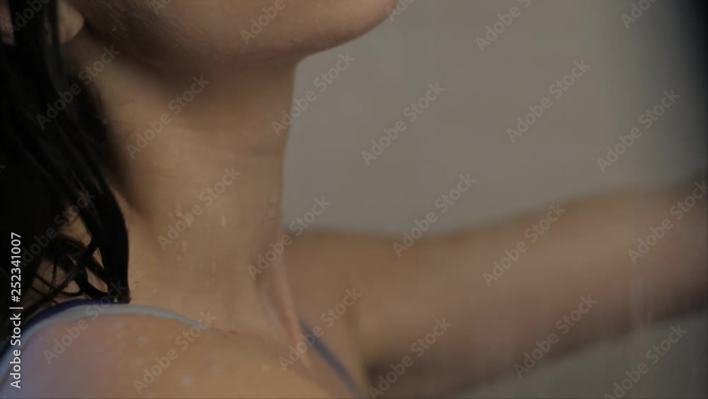 Woman in shower in swimsuit, shallow depth of field. Slow motion Woman in shower in swimsuit, shallow depth of field. Slow motion